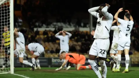 Port Vale players have their heads in their hands after a chance against Barrow goes begging