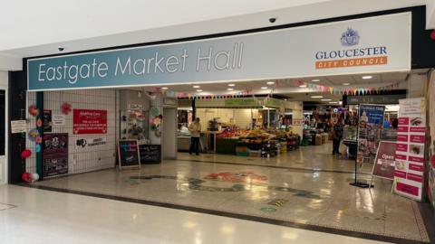 The entrance to Eastgate Market Hall - a dated indoor market at a shopping centre, where trader stalls can be seen inside.