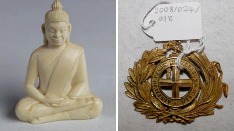 A carved ivory buddha with robes in a cross-legged position. It sits next to a circular belt buckle with a laurel motif with the words "Auspicio Regis et Senatus Angliae".