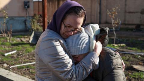 A woman hugs another woman who is crying