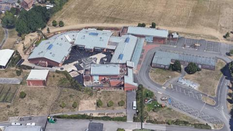 An aerial view of the school. It is a mixture of single storey buildings with a car park.