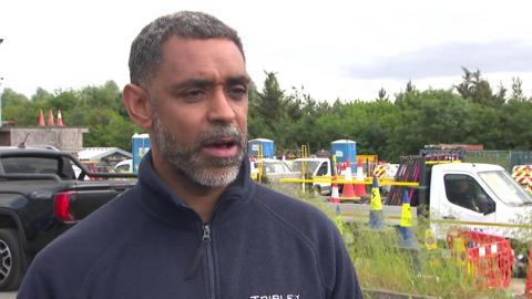 A man in a blue fleece jacket is standing in front of some cars. 