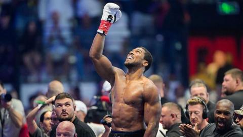 Bare-chested Anthony Joshua raises a fist and looks to the skies after his win