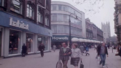 Still from archive footage of The Hayes in Cardiff city centre, with shoppers walking near buildings, including Habitat and Howells