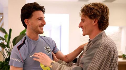 Anthony Gordon greets England team-mate Declan Rice as he arrives in Florida before the 2026 World Cup