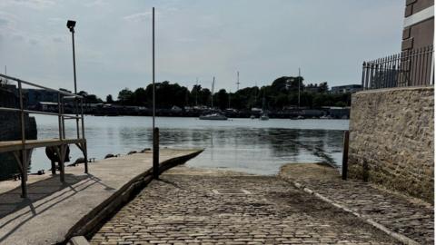 Admiral's Hard Slipway in Plymouth on a cloudy warm day. The tide is in and covering most of the slipway.