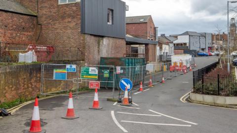 Derelict units in Cheapside Spennymoor surrounded by metal fencing and traffic management measures