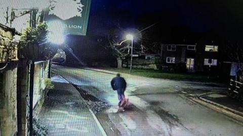 A scooter driver hitting a pothole in the road and about to go over.