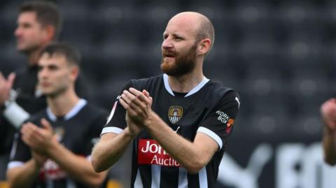 Curtis Edwards applauds crowd in home black and white strpied kit at the end of a game