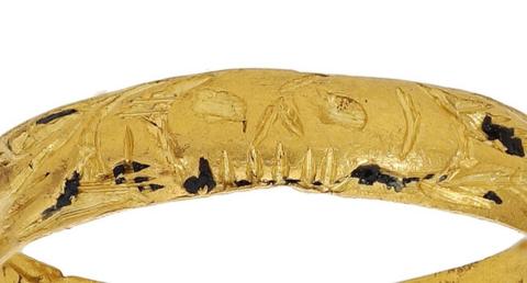 The gold ring has markings including what looks like a skull in this close up photo.