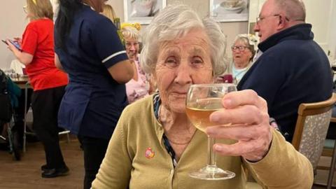 Hilda Jackson holding up a glass of wine to the camera