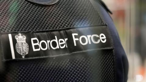 A stock image of a person wearing a UK Border Force vest. Is it a close up picture of the writing on the front. 