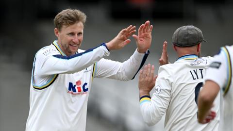 Joe Root high-fives team-mates Adam Lyth (number nine) after taking a wicket for Yorkshire