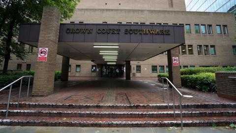 Southwark Crown Court exterior with gold letters on black background above red brick steps with a sign reading "exit"