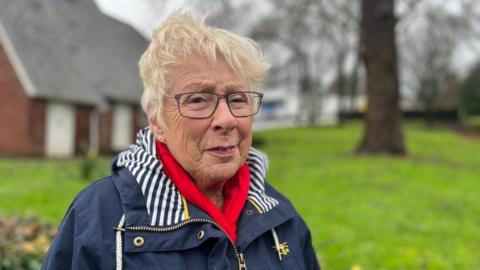 Susie Colley wearing a red scarf and a blue coat with a blue and white striped lining