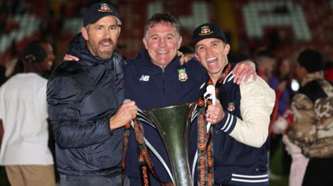 Ryan Reynolds, Phil Parkinson and Rob Mac pose with the National League trophy
