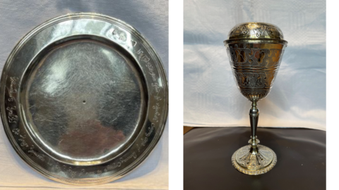 A silver plate on the left and a covered chalice on the right. Both of the items belong to a church.
