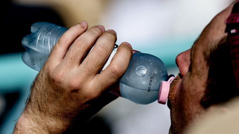 Man drinks from a cold bottle of water