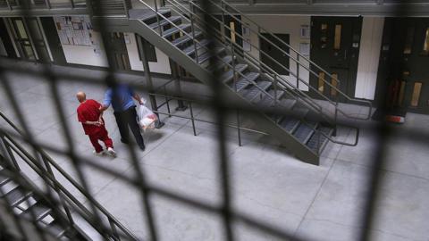 A guard escorts an immigrant detainee from his 'segregation cell' back into the general population at the Adelanto Detention Facility on November 15, 2013 in Adelanto, California.