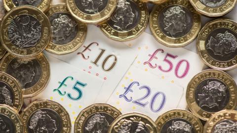 A series of coins on top of four bank notes.