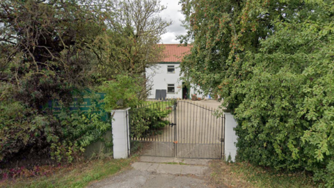 A gated off property with a sign advertising dog kennels and a cattery.