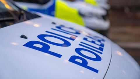 Close-up of the bonnet of a Police Scotland car with blurred police cars in the background 