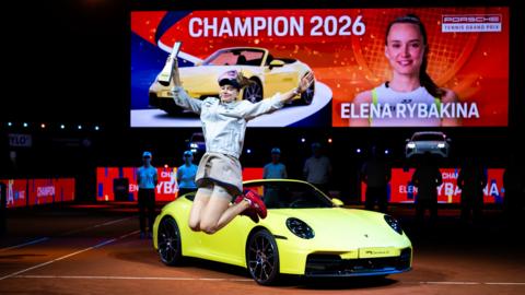 Elena Rybakina celebrates her victory in Stuttgart in front of the sports car that forms part of her winner's prize