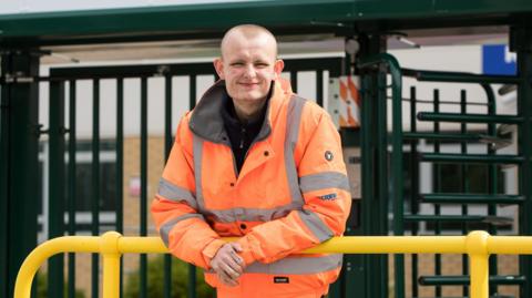 A young man wearing an orange vi-viz jacket