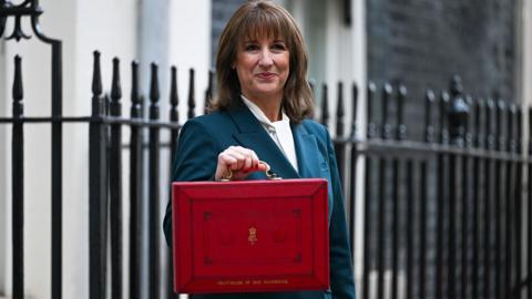 Chancellor Rachel Reeves standing in Downing Street with her Budget red box.