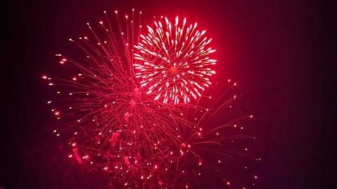 A firework explodes in the sky, producing bright red light