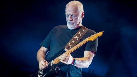 Gilmour during a concert where he is playing a black guitar