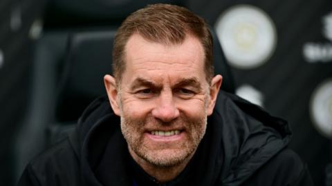 Harrogate Town manager Simon Weaver head shot sat in dug-out smiling
