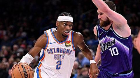 Shai Gilgeous-Alexander of the Oklahoma City Thunder attempts to drive past Svi Mykhailiuk of the Utah Jazz