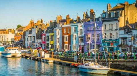 Harbourside with boats along a pontoon and a coloured terrace.