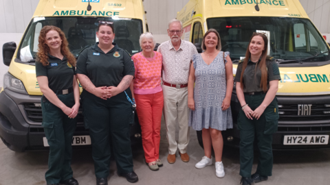A man with his wife and daughter stood next to three female paramedics in front of two ambulances