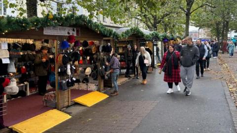 A row of stalls at York's Christmas market with shoppers passing by. 