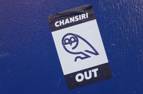 A sticker bearing the slogan 'Chansiri Out' on a wall at Sheffield Wednesday's Hillsborough stadium