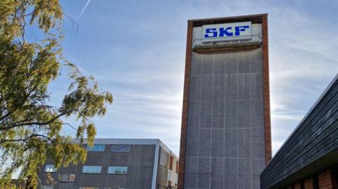 SKF Factory. Its shows a talk concrete building with SKF written at the top in blue letters 