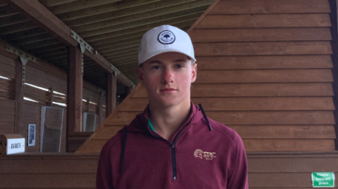 Golfer Conor McKenna, stood at the Guernsey L'Ancresse Driving Range, in a maroon coloured quarter zip and white cap