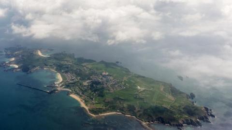 Aerial view of Alderney from plane flying above the island. Below the runway is visible to the right of the island.