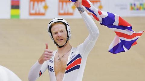 Stephen Bate celebrates by holding up a British flag behind pilot Christopher Latham