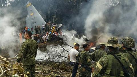 Soldiers and rescuers  are seen near a Colombian Air Force C-130 Hercules plane from which thick smoke is rising after the aircraft crashed during take-off in Puerto Leguízamo, Colombia. Photo: 23 March 2026