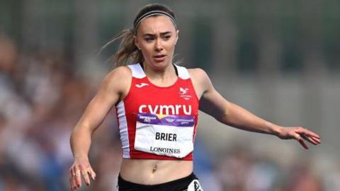 Hannah Brier runs in a red Cymru vest at the Commonwealth Games in Birmingham in 2022.