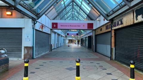 The entrance of the old Riverside shopping centre with boarded up shops