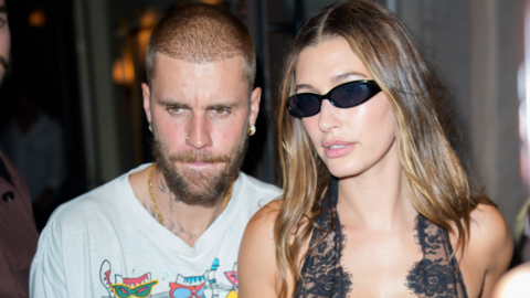 Justin Bieber (left) and his wife Hailey (right).
Justin is wearing a white graphic t-shirt with colourful designs, has a closely shaved hairstyle and facial hair, and gives off a relaxed, casual vibe. Hailey contrasts that with a bold fashion statement—dressed in a black lace outfit, wearing sunglasses indoors, and sporting long, wavy hair that adds to the glam look. 