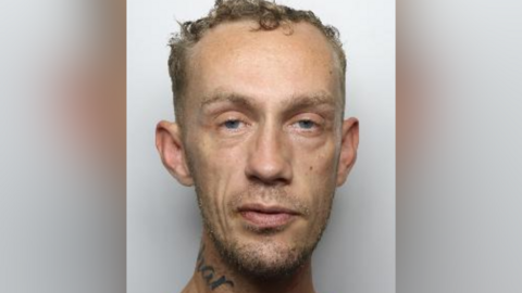 Custody picture of Andrew McMinn, a man with short curly hair and a tattoo on his neck.