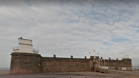 Fort Perch Rock, an early 19th century coastal defence in New Brighton. It is a sandstone-built fortress with battlements, and a ramp leading up to its entrance.