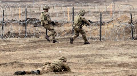 NATO's Allied Reaction Force members approach barbed wire during the NATO exercise Steadfast Dart in Romania.