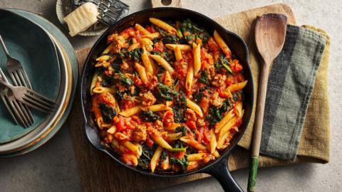 A large pan of sausage and penne pasta.