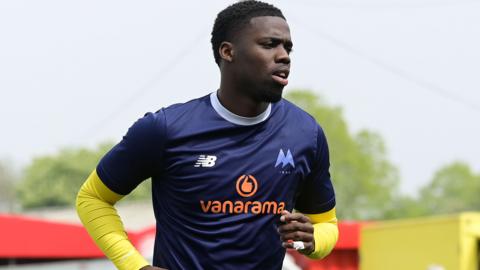 Omar Mussa in navy blue Torquay United warm-up top with yellow undershirt visible on arms